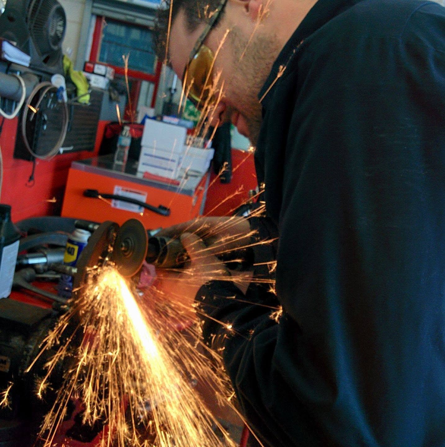 Mechanic grinding metal during custom fabrication