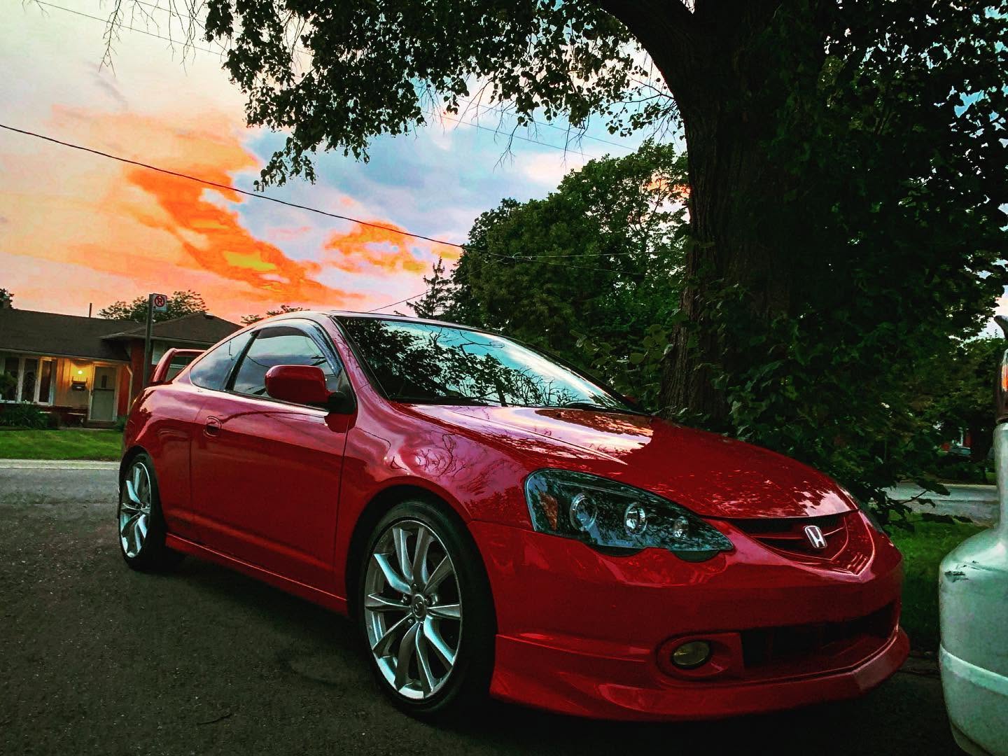 Red coupe photographed outdoors at sunset